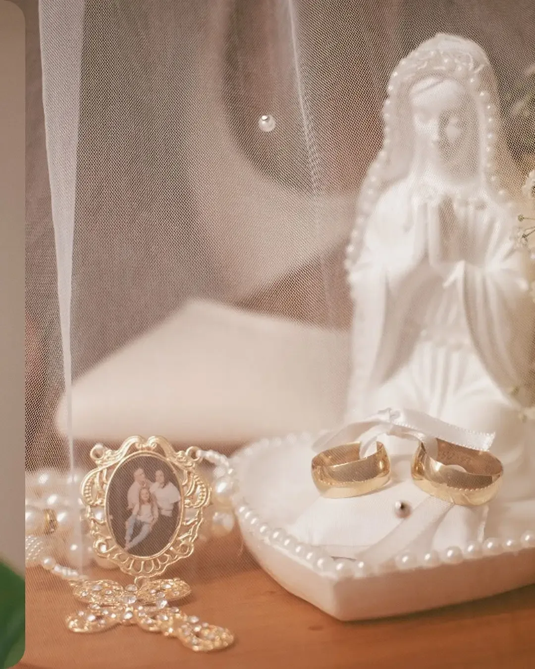 Alianças e joias sobre um suporte ao lado de uma imagem religiosa.