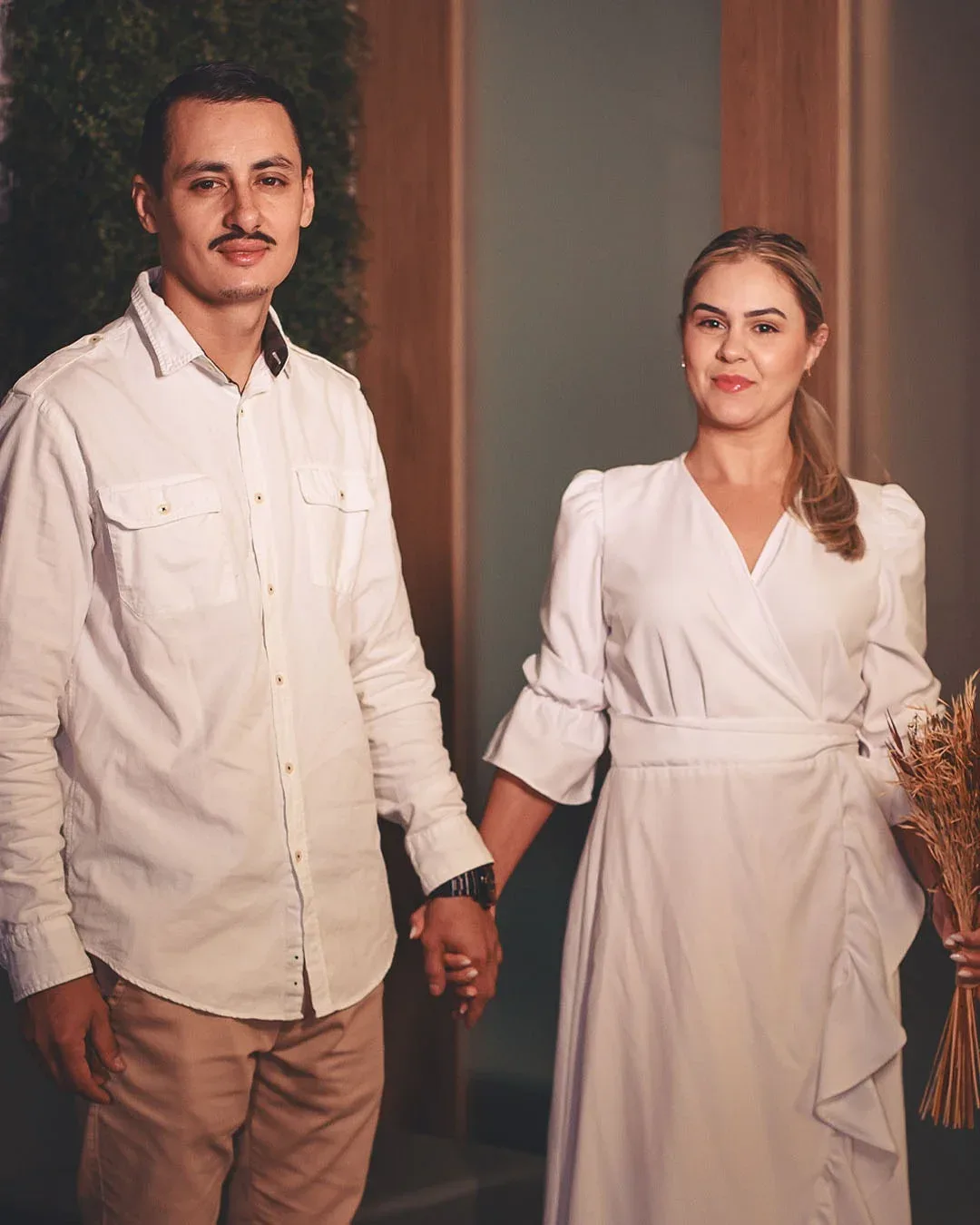 Retrato de casal com roupas claras durante o casamento civil.